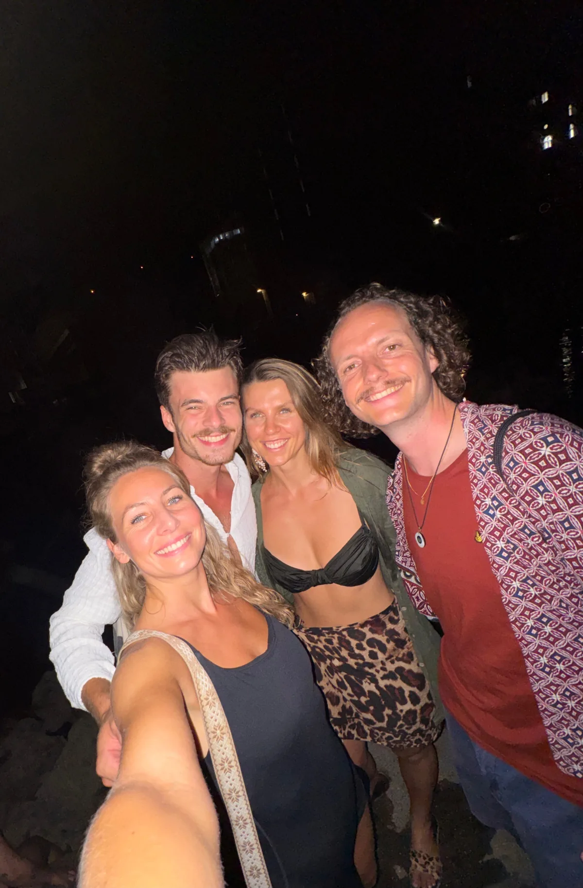 Vier Freunde lachen nachts eng zusammen in die Kamera
