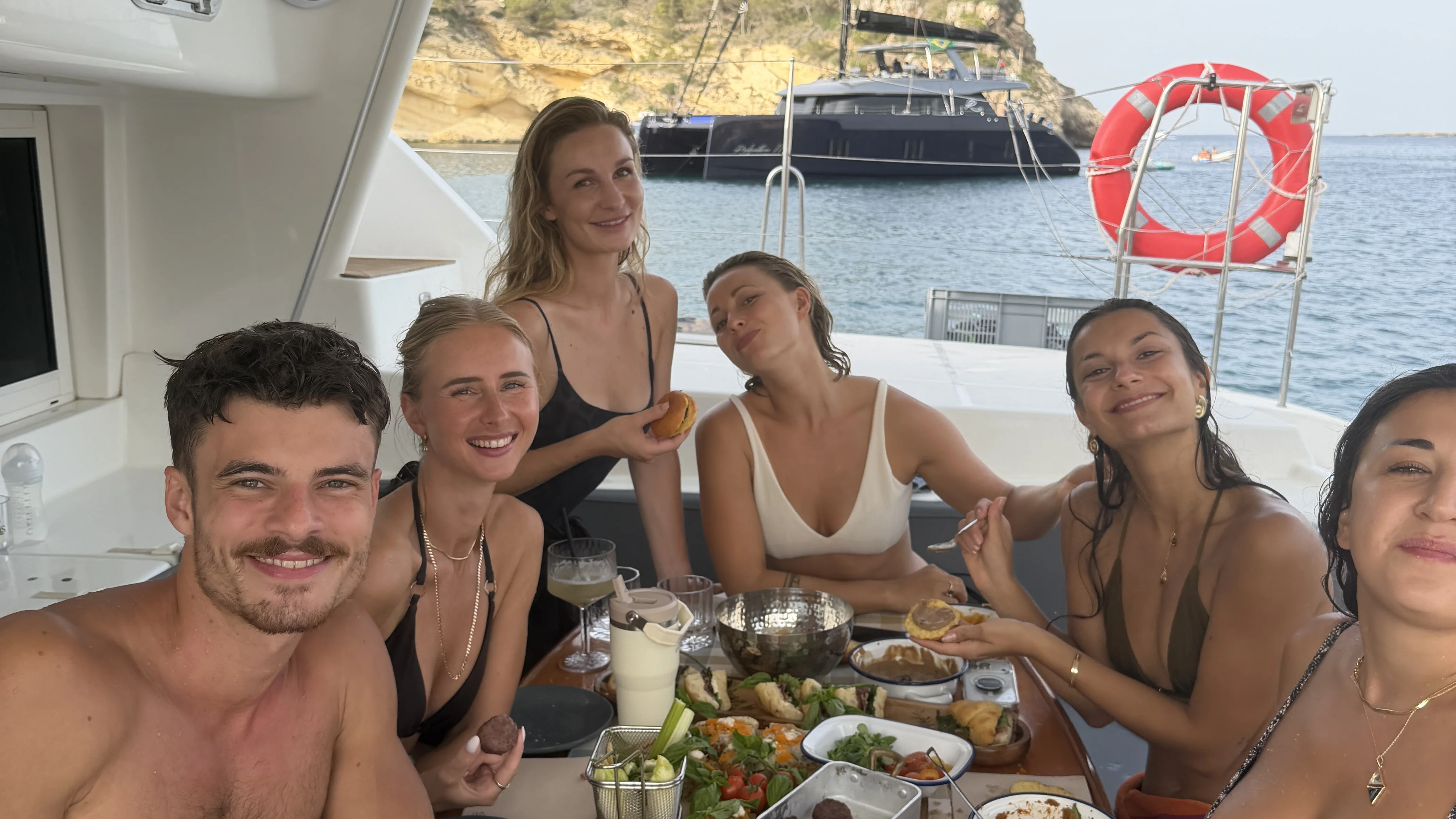 Gruppe sitzt gemeinsam beim Essen auf einem Boot
